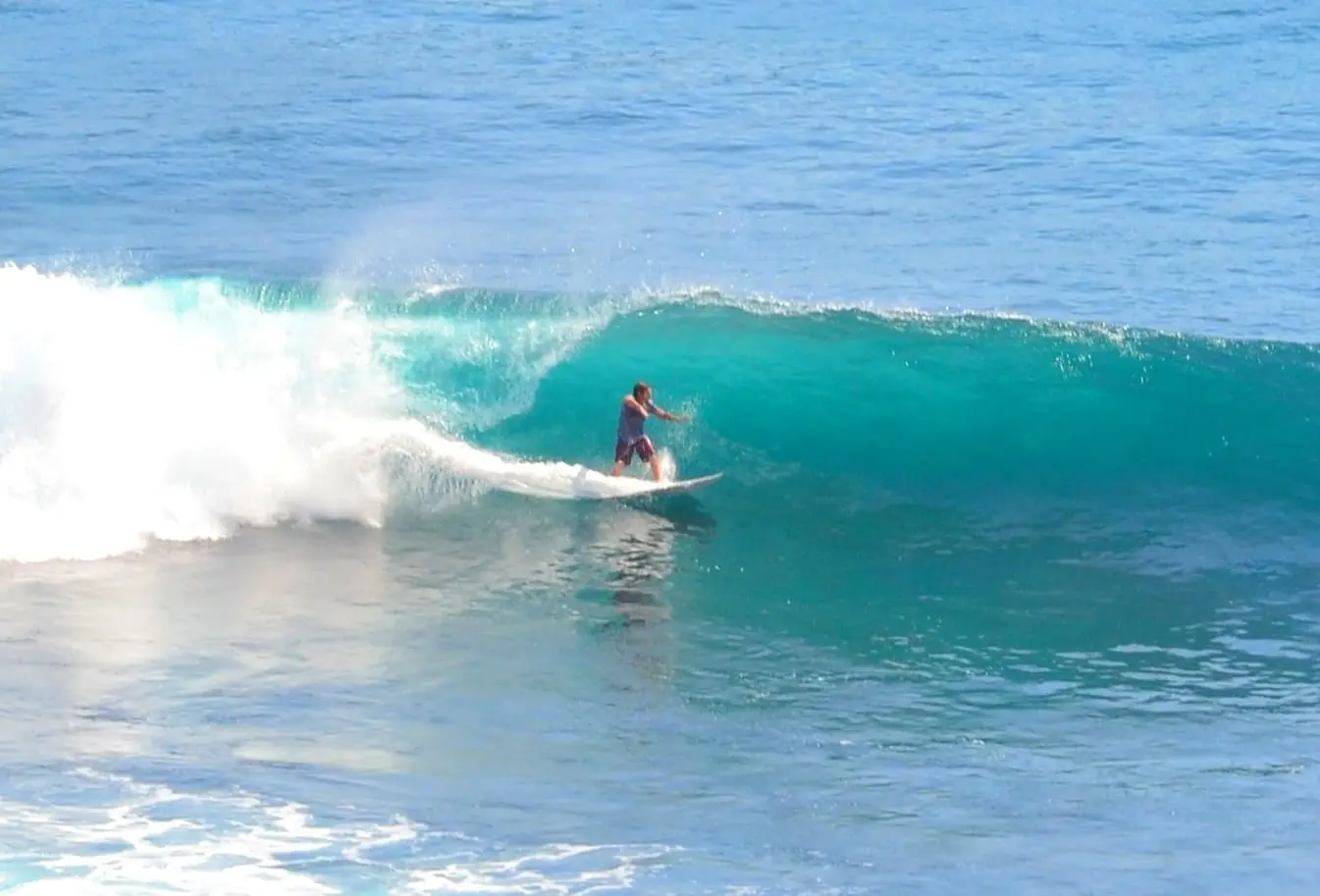 Surfer riding a glassy wave off the west coast of Bali