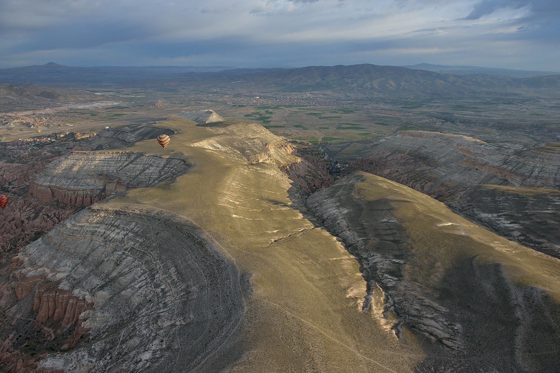 View from inside a hot air balloon basket at sunrise over Cappadocia valleys