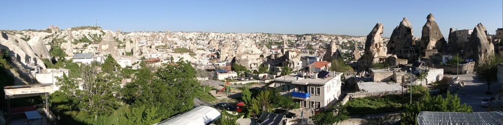 Panoramic view over Goreme village from a cave hotel terrace at golden hour, Cappadocia