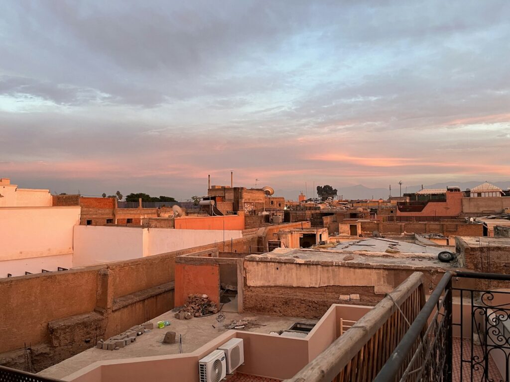 Rooftop view over the terracotta rooftops and minarets of Marrakech medina at dusk