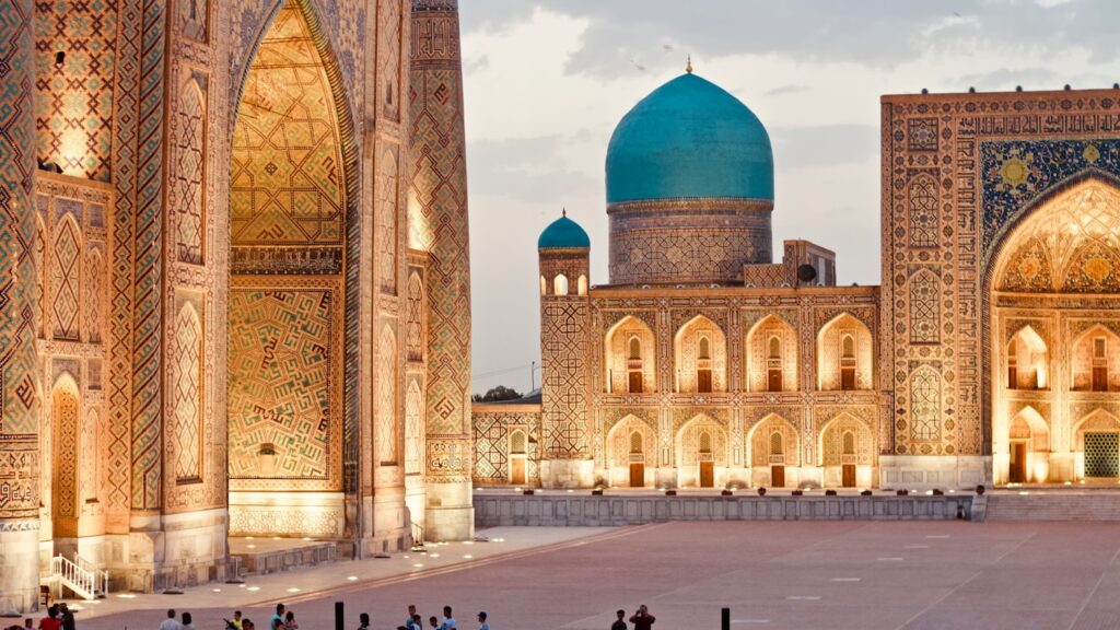 The Registan square in Samarkand, Uzbekistan, with its three towering tiled madrasas glowing in golden evening light
