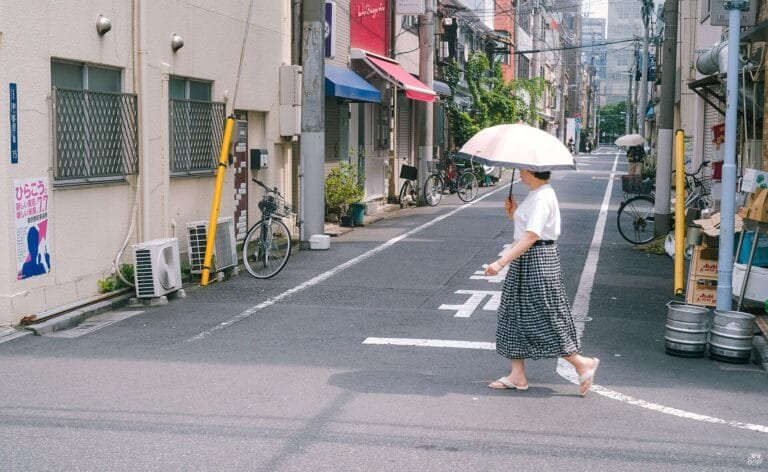 Woman with a parasol crossing a quiet street in Tokyo, Japan