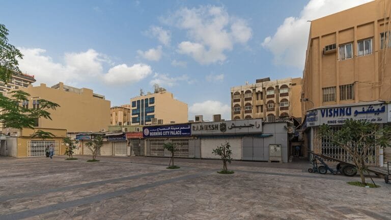 Low-rise shopfronts and an open lot on a quiet street in Dubai, UAE