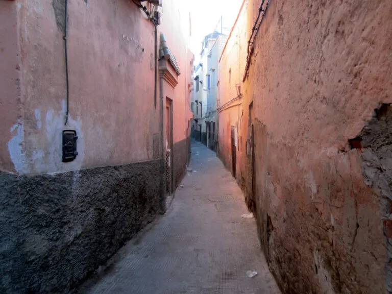 Narrow alley between pink earthen walls in the Marrakech medina, Morocco
