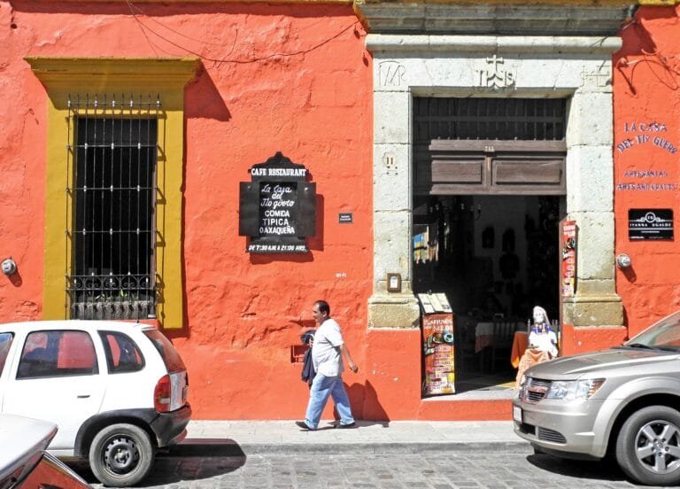Bright red colonial building with a carved doorway on a street in Oaxaca, Mexico