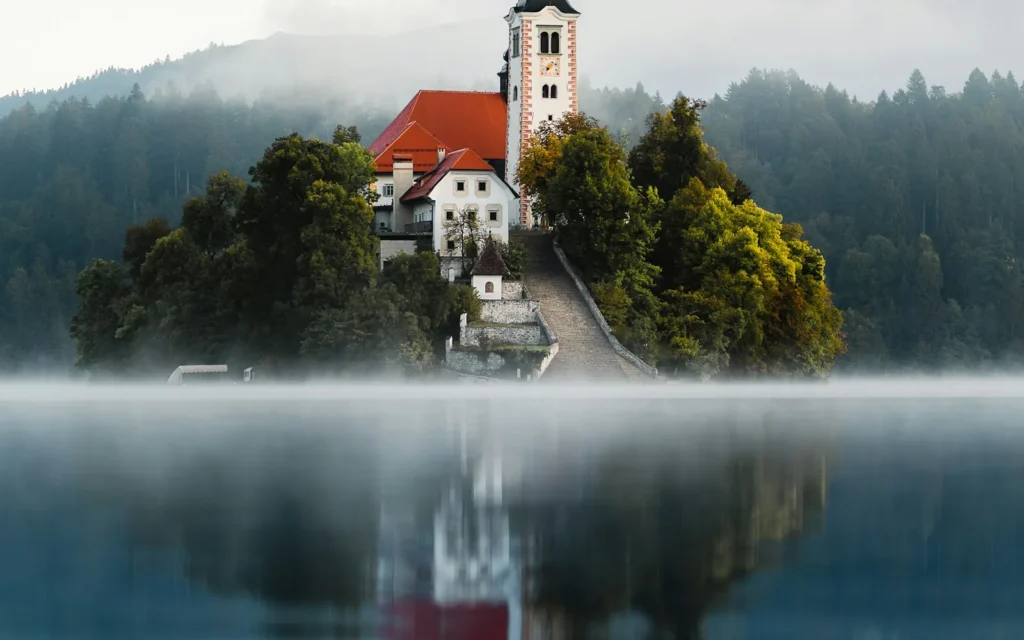 The island church on Lake Bled reflected in misty water, Slovenia