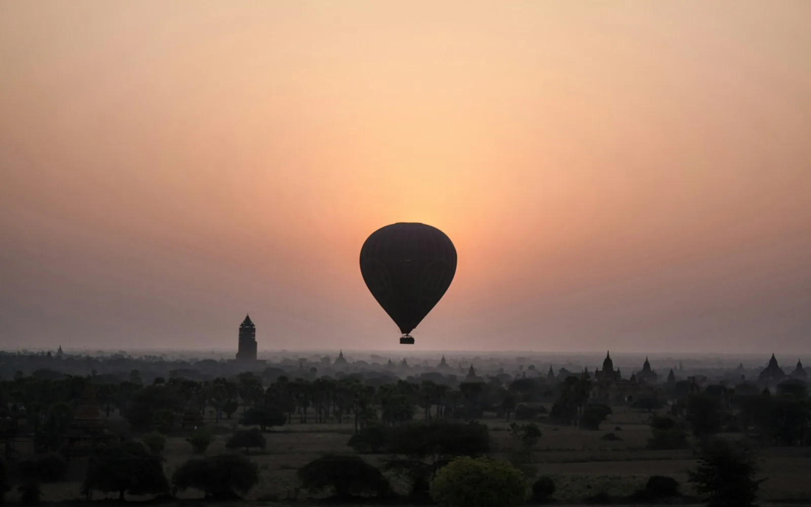 A hot-air balloon over the ancient temple plain of Bagan, Myanmar at golden hour
