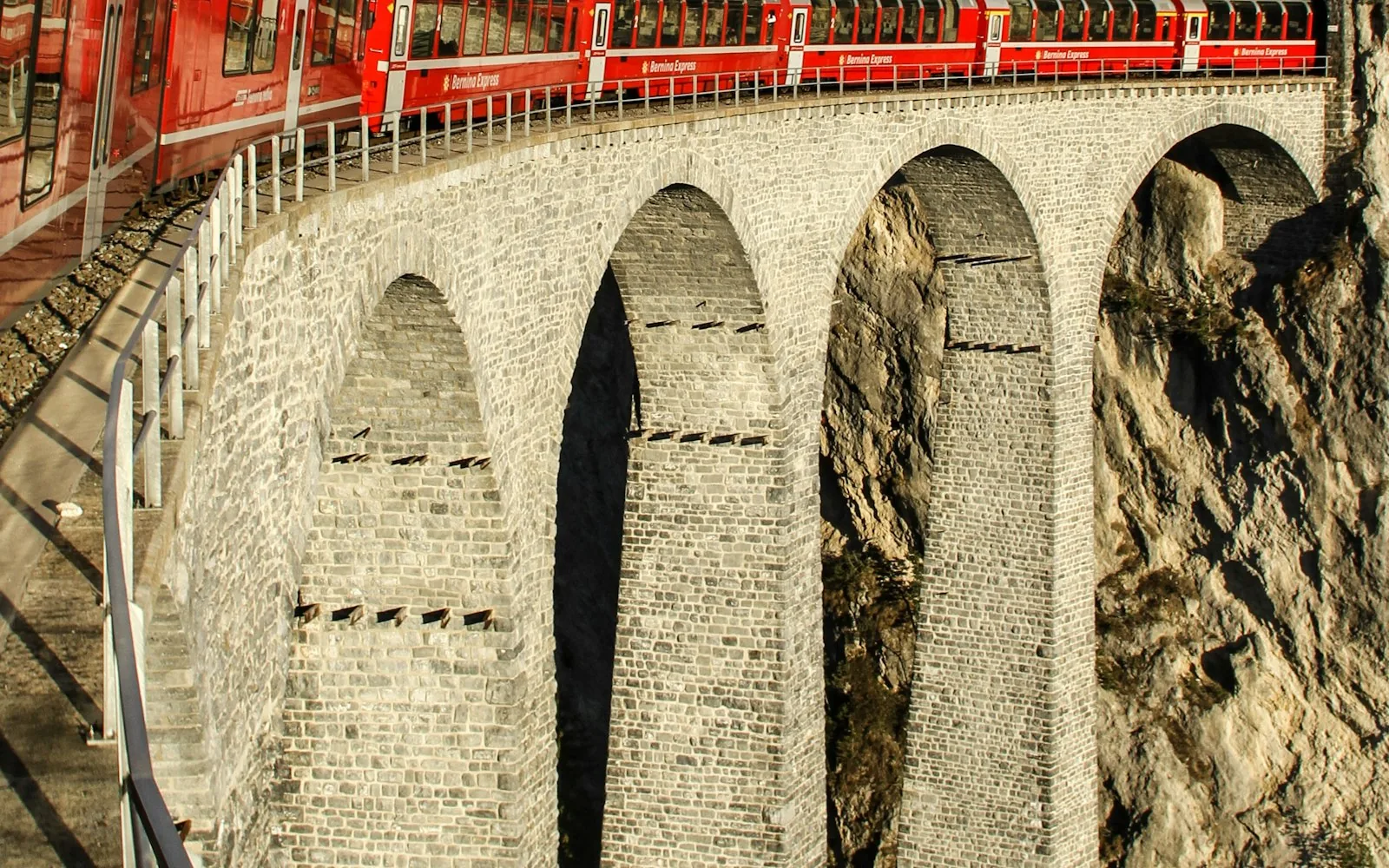 A red train crossing the Landwasser Viaduct on a scenic Swiss rail journey