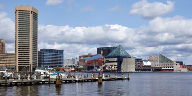 Boats moored along Baltimore’s Inner Harbor with the National Aquarium and downtown towers behind