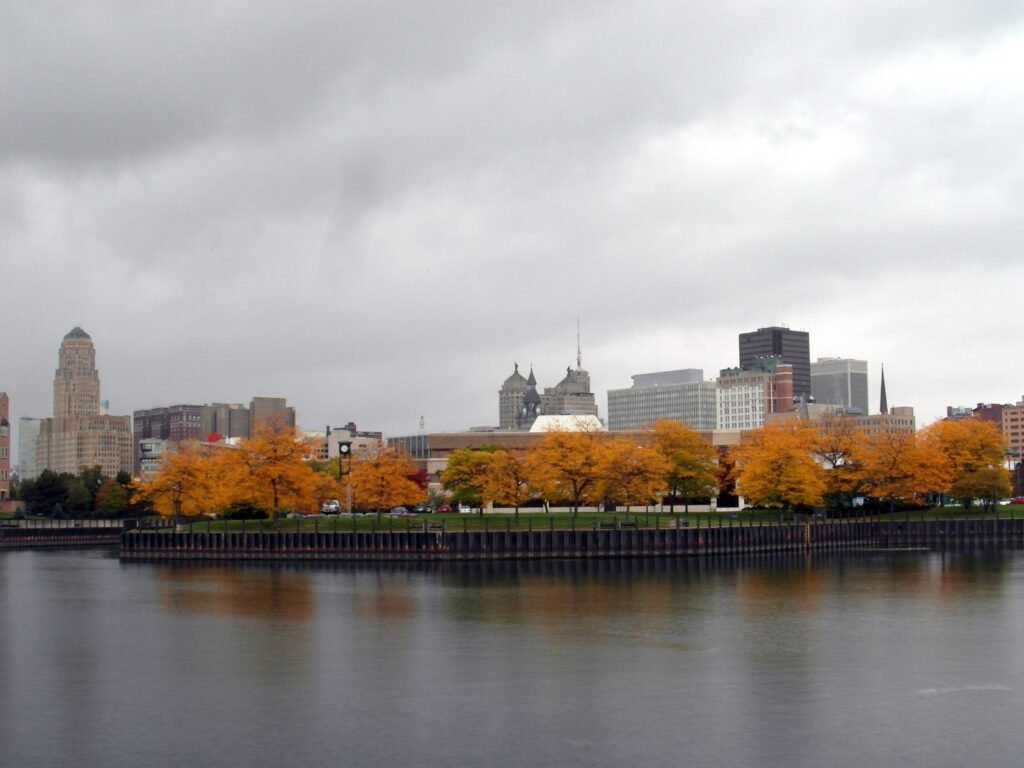 The Buffalo skyline behind a band of autumn trees, seen across the water from Erie Basin Marina