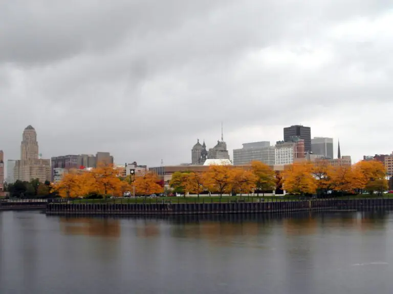 The Buffalo skyline behind a band of autumn trees, seen across the water from Erie Basin Marina