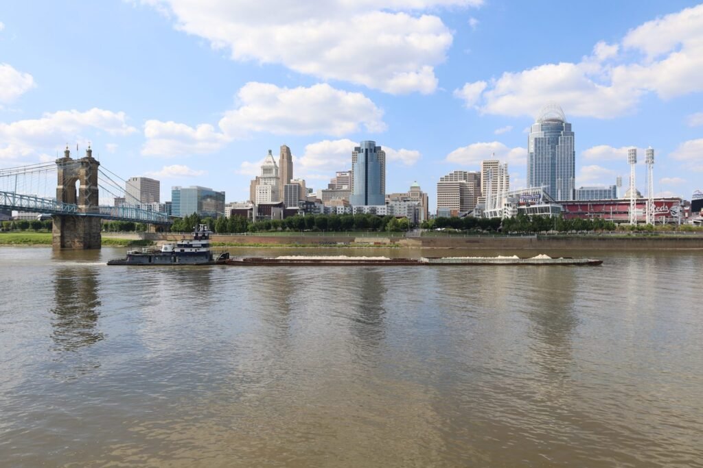 The Cincinnati skyline across the Ohio River with the Roebling Suspension Bridge at left and a barge passing