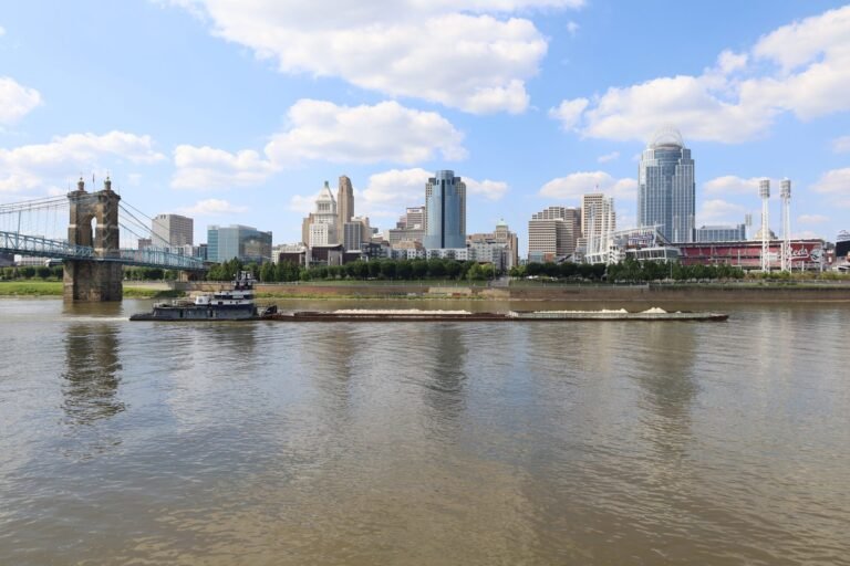 The Cincinnati skyline across the Ohio River with the Roebling Suspension Bridge at left and a barge passing