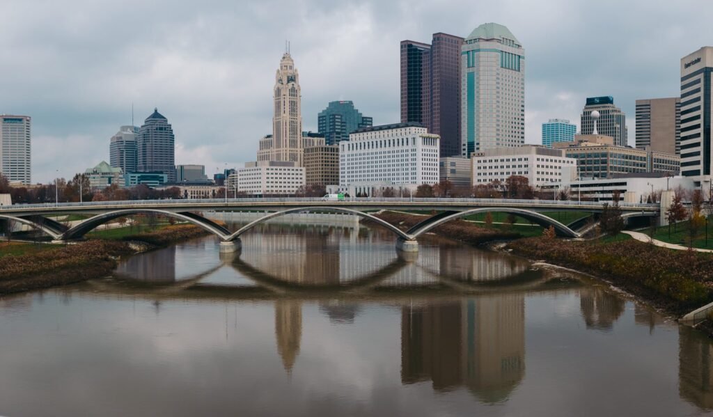 The Scioto River reflecting an arched bridge and the Columbus skyline, with the LeVeque Tower at centre