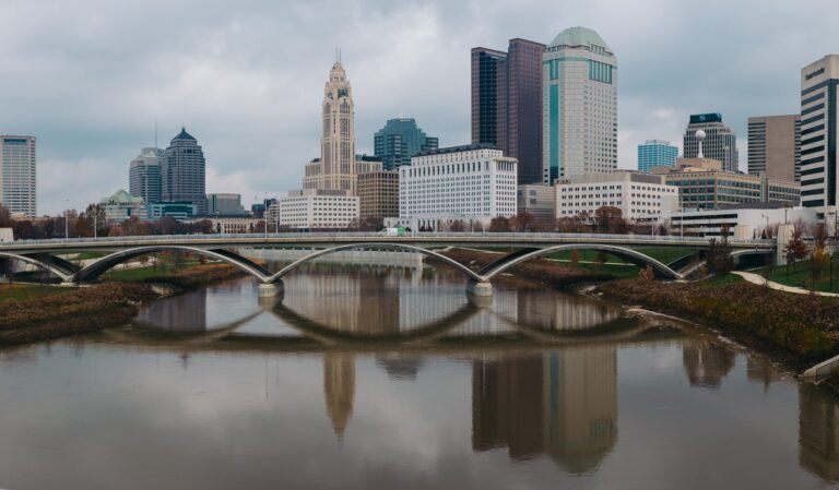 The Scioto River reflecting an arched bridge and the Columbus skyline, with the LeVeque Tower at centre