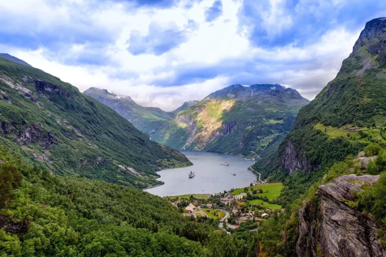 Green cliffs dropping to the deep blue water of the Geirangerfjord in summer, Norway