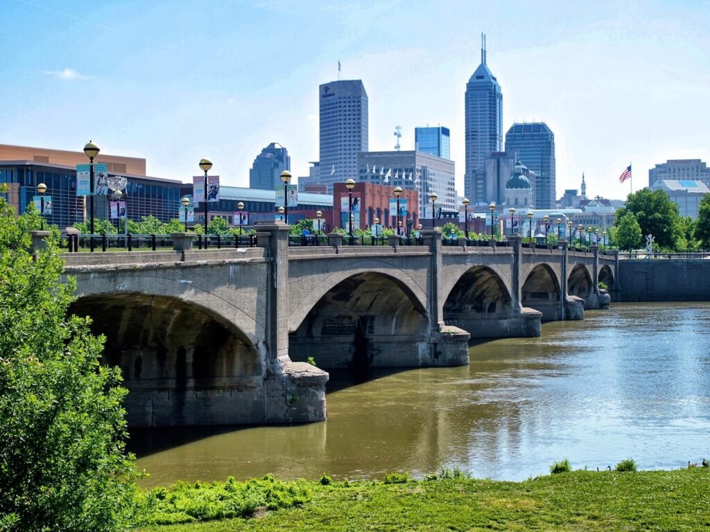 A stone arch bridge over the White River with the Indianapolis skyline rising behind it