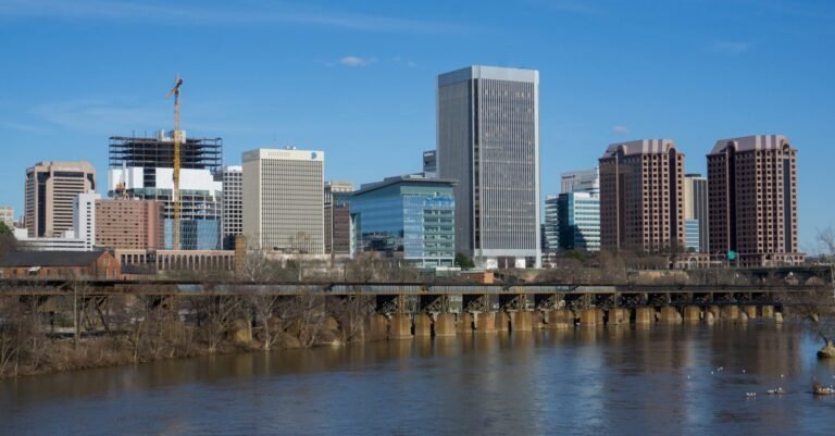 The Richmond skyline above the James River with a low rail bridge crossing in the foreground
