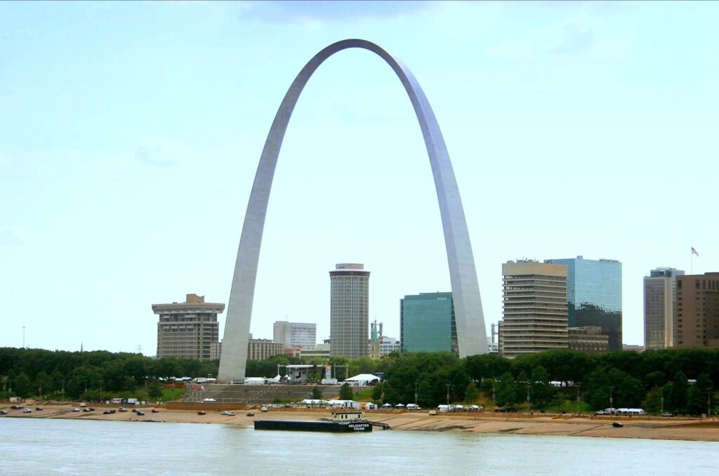 The Gateway Arch standing above the St. Louis riverfront and downtown towers, seen across the Mississippi