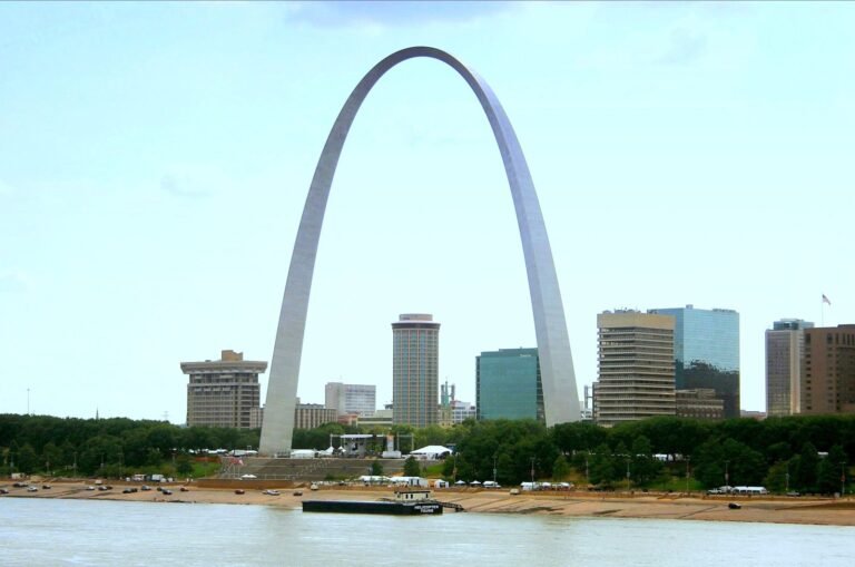 The Gateway Arch standing above the St. Louis riverfront and downtown towers, seen across the Mississippi
