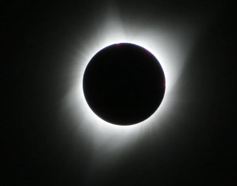 The sun's corona glowing around the black disc of the moon during a total solar eclipse